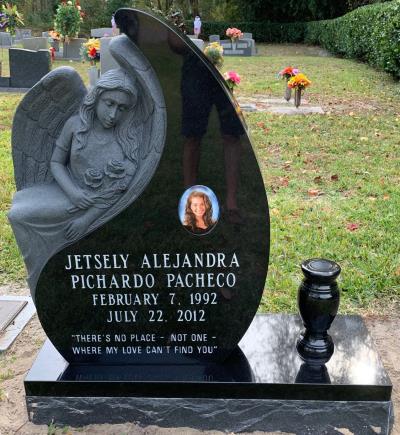 individual upright black granite headstone in the shape of an angel and tear drop with a portrait and flower vase